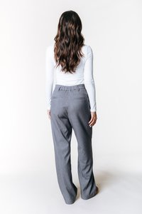 Pantalons gris à rayures avec une coupe décontractée, dotés d'une taille plate et de deux poches arrière. Modèle portant un haut blanc à manches longues.