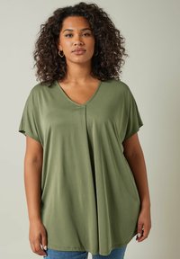 Top verde oliva con scollo a V e maniche corte. Realizzato in un tessuto morbido, presenta un design ampio e fluido con un dettaglio di cucitura centrale.