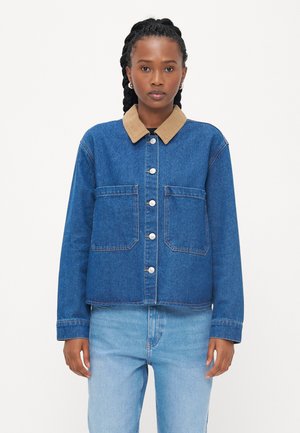 Denim jack met een lichtbruine corduroy kraag, voorzakken en zilveren knopen. Gestyled met lichtblauwe jeans met een gladde textuur.