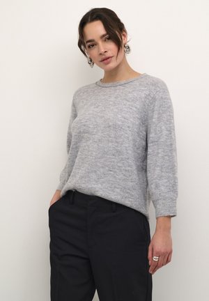 Lichtgrijze gebreide trui met een relaxed fit, ronde halslijn en driekwartmouwen. Gecombineerd met donkere broeken, met een zachte textuur.