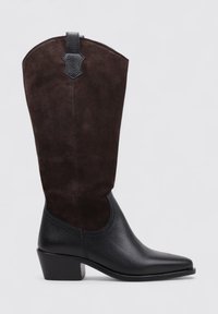 Botas de cowboy hasta la rodilla con una sección inferior de cuero negro y una parte superior de ante marrón oscuro, que cuentan con una pequeña pestaña negra en la parte posterior y un tacón cuadrado.