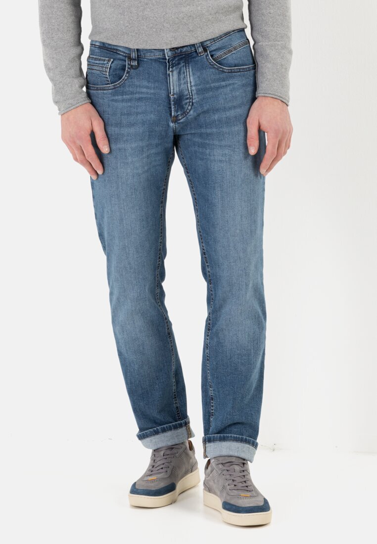 Jeans bleu clair en denim, avec une coupe droite, un design à cinq poches et un léger délavage. Associés à des baskets grises.
