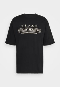 Černé bavlněné tričko s kulatým výstřihem, se bílým grafickým textem "SUNDAY SESSIONS" a sportovními postavami nad ním. Krátké rukávy.