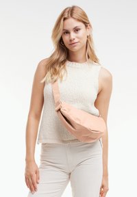 Borsa a tracolla rosa in tessuto con forma arrotondata, texture morbida e tracolla regolabile, indossata diagonalmente sul corpo.
