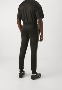 Black athletic outfit featuring a t-shirt and pants. Pants have a slim fit with a contrasting side stripe, elastic waistband, and pockets.