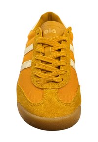 Zapatillas amarillas hechas de tela sintética con acentos de ante. Presenta dos rayas blancas, puntera redondeada y suela de goma texturizada.