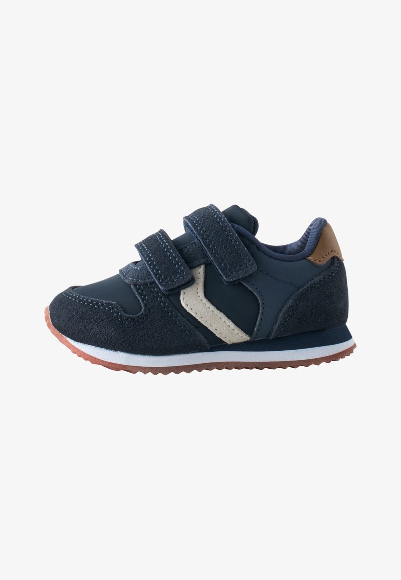 Baskets bleu marine pour enfants avec double fermeture Velcro, détail latéral beige, languette de talon marron et semelle en caoutchouc marron.