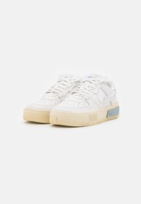 Białe skórzane sneakersy z perforowanym czubkiem, płaskimi sznurowadłami oraz kremową gumową podeszwą. Posiadają niebieski akcent po boku i teksturowany obcas.