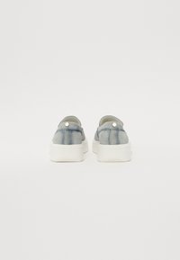 Bottines en suède bleu clair, à enfiler, avec un col rembourré, une semelle en caoutchouc blanche et un détail de bouton décoratif à l'arrière.