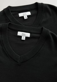 Deux pulls noirs à col en V avec col côtelé, taille moyenne, coupe classique, étiquetés "Next" et fabriqués au Bangladesh.