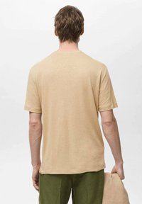Tricou bej cu mânecă scurtă, cu guler rotund, fabricat dintr-un material moale. Linia de jos este dreaptă iar croiala pare confortabilă.