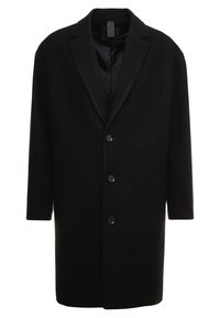 Cappotto in lana nera con colletto a pistagna, chiusura a cinque bottoni e maniche lunghe con un rivestimento interno liscio. Dettagli in texture herringbone.