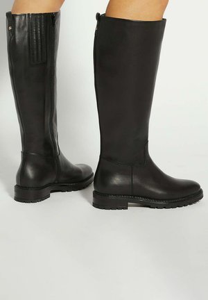 Black knee-high boots made of smooth leather. Features a side zipper, textured panels, and a rugged sole with a decorative stitch detail.