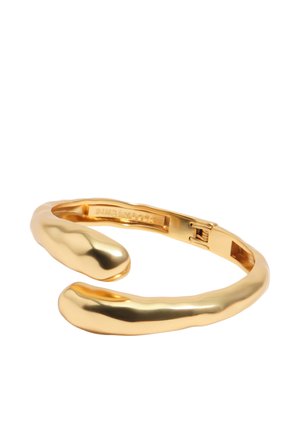 Gold-toned, polished metal cuff bracelet with a hinge clasp, featuring smooth, slightly irregular rounded ends and a reflective surface.