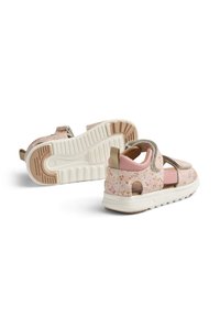 Vaaleanpunaiset kukkakuosiset sandaalit, joissa on tarranauhat, avoin malli, kevyt pohja ja teksturoitu pohja. Sandaaleissa on beige yksityiskohta kannassa.
