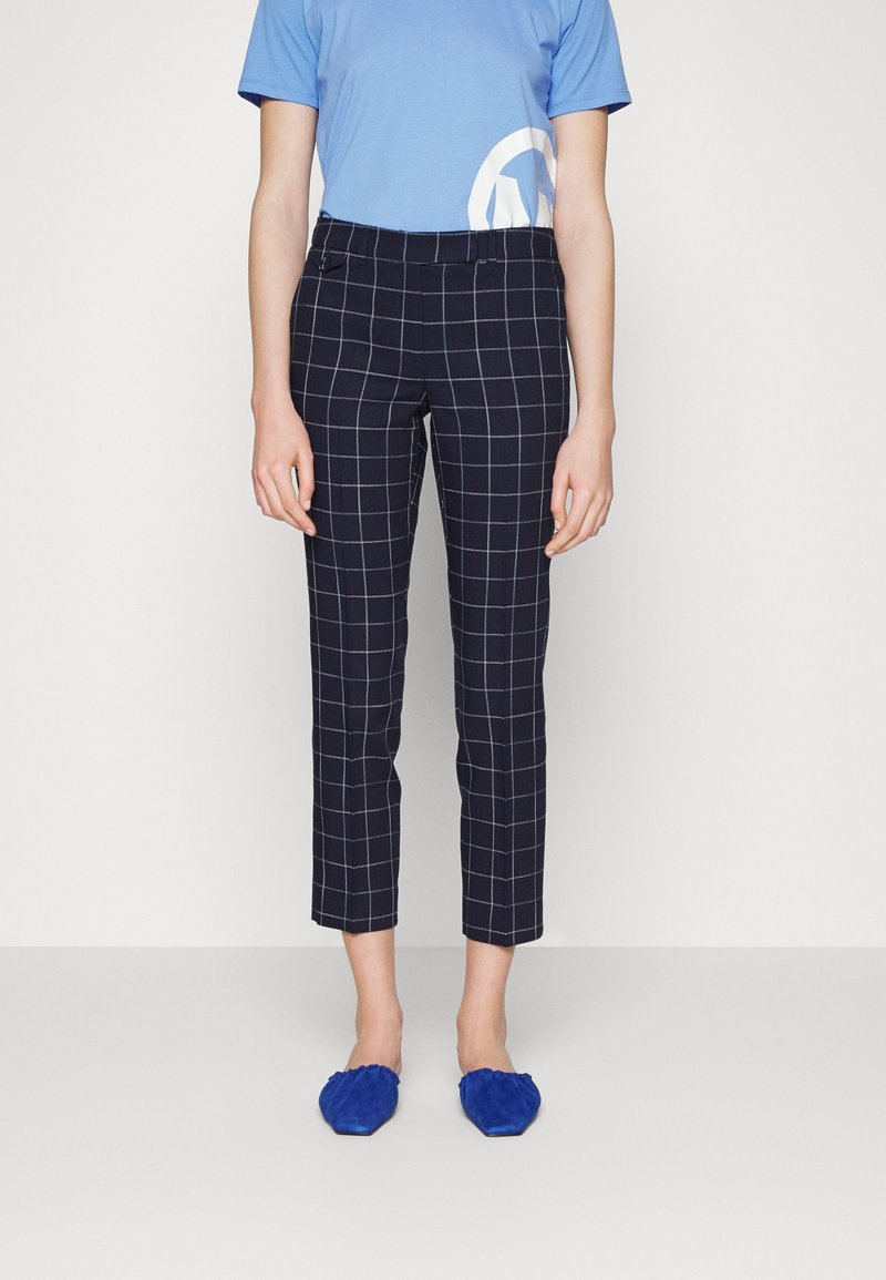 Marinblå rutiga byxor som slutar vid anklarna med en tajt passform, med ett rutig mönster i ljusblått. Matchas med en blå t-shirt och blå skor.