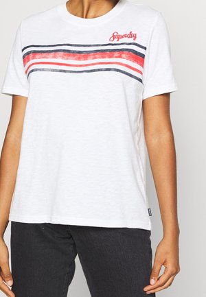 Person wearing a white t-shirt with red, white, and black horizontal stripes and red "Superdry" text on the chest.