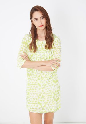Vestido de manga corta en verde claro con un patrón geométrico, que presenta un cuello redondo y un diseño a la altura de la rodilla, hecho de tejido liviano.