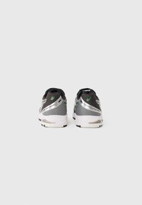 Sport shoes in grey with black and metallic accents, featuring a mesh upper, rounded toe, and cushioned sole. Green detailing near the heel.