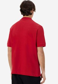 Polo shirt rosso a maniche corte in cotone, con colletto classico e design minimalista. Texture liscia e colore uniforme.
