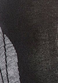 Tissu noir à côtes avec des accents argentés. Présente un motif texturé avec des rayures horizontales et des sections lisses et élégantes.