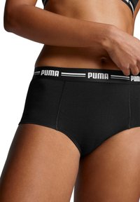 Zwarte katoenen slip met een brede tailleband met witte "PUMA" branding, een gladde textuur en een middelhoge pasvorm. Eenvoudig en functioneel ontwerp.
