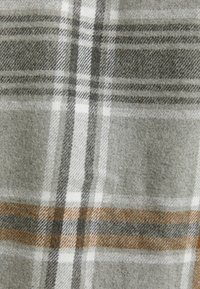 Manta de lana con un patrón de cuadros en gris, blanco y naranja. Textura suave, con franjas alternas y detalles a cuadros.