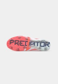 Predator-jalkapalloilyksikkö, jossa on läpinäkyvä pohja, kirkkaat vaaleanpunaiset koristeet ja rohkea "PREDATOR"-painatus. Varustettu nappuloilla pidon parantamiseksi.