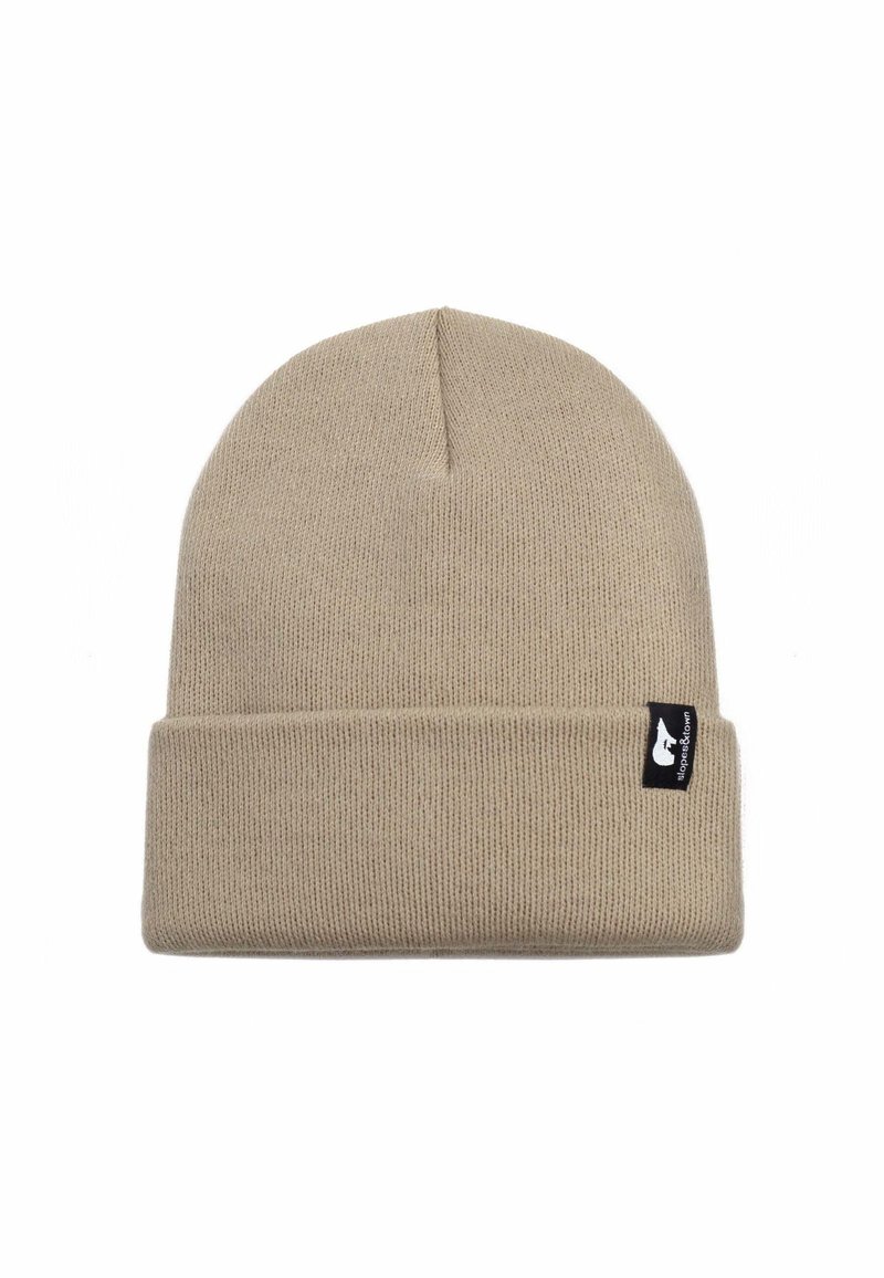 Berretto lavorato a maglia color beige con risvolto, dotato di un piccolo etichetta nera sul lato. Il materiale sembra morbido ed elastico.