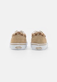 Zapatos de skate de gamuza color marrón claro con un patrón de tela a cuadros marrones, suela de goma blanca y logo de Vans en el talón, vista desde atrás.