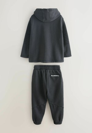 Donkergrijze hoodie en bijpassende joggers. De hoodie heeft een grote capuchon en textuur mouwen. De joggers hebben een elastische tailleband en logo-detail.