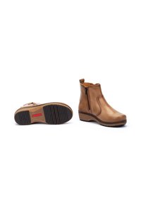 Bottines en cuir marron avec une fermeture éclair sur le côté, semelle en wedge texturée et finition lisse. La semelle extérieure présente un motif pour une meilleure adhérence.