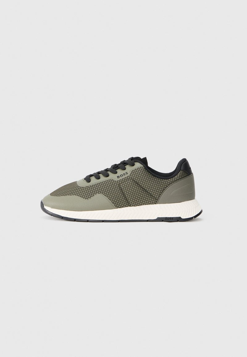 Gröna mesh-sneakers med svarta detaljer, strukturerad ovandel, platta snören och en vit, gummibeklädd sula. Logotypen syns på sidan.