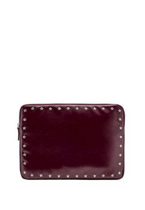 Pochette rectangulaire en cuir rouge foncé avec une fermeture éclair et de petits clous argentés en forme d’étoile bordant les contours avant.