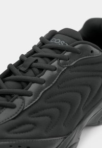 Sapatilha atlética preta com tecido em malha texturizado e detalhes em couro sintético suave. Apresenta cordões resistentes e um padrão em ziguezague na lateral.