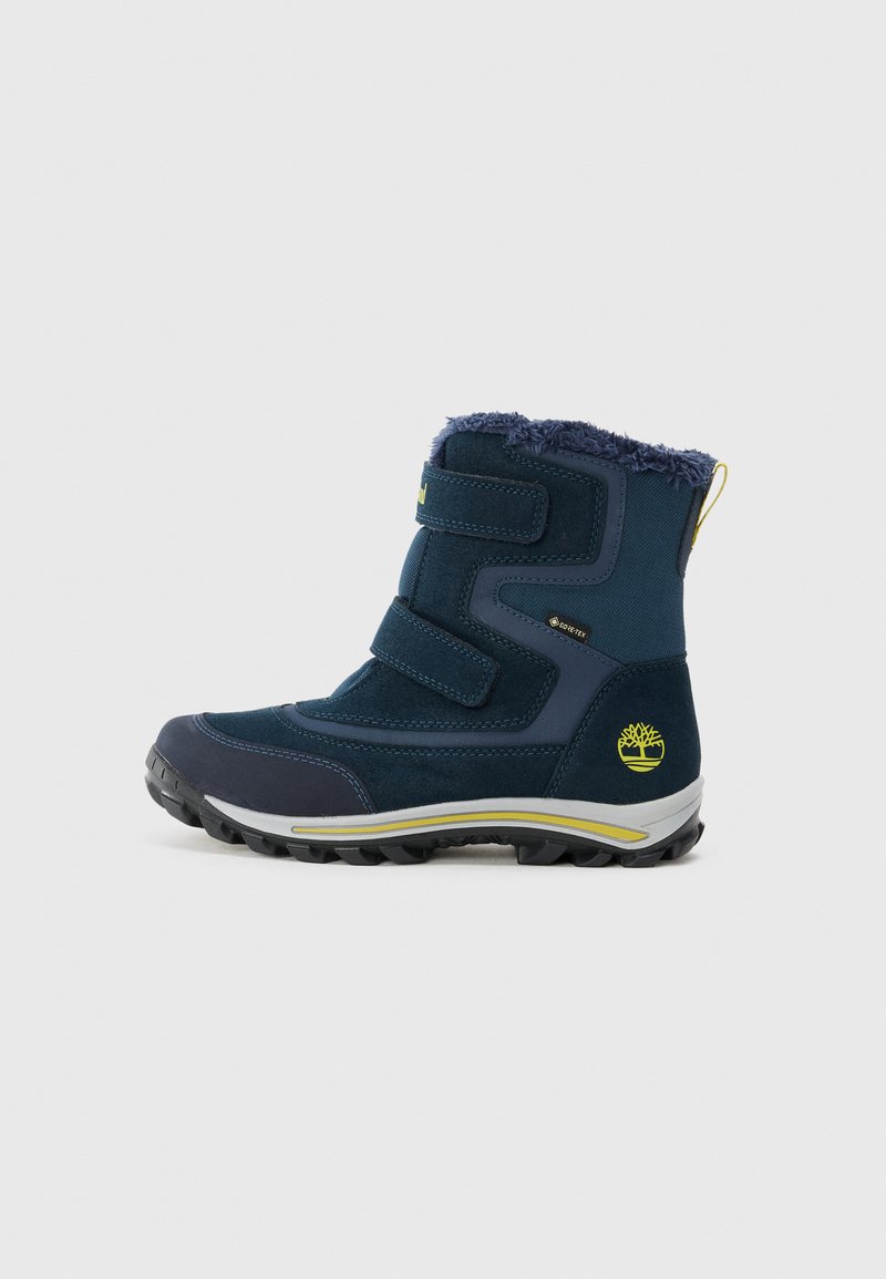 Stivale invernale blu navy con parte superiore in materiale sintetico, colletto foderato in pelliccia, due cinturini in Velcro, suola in gomma texture e dettaglio logo verde sul lato.