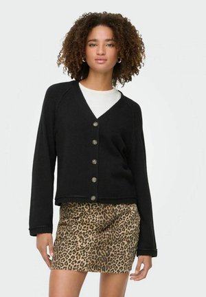 Cardigan nero con scollo a V, chiusura con bottoni e bordi a costine, abbinato a una gonna in stampa leopardata, con texture liscia e design aderente.