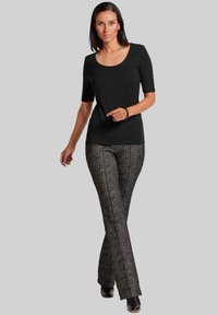 Schwarzes, enges Kurzarmoberteil kombiniert mit strukturierten schwarz-weißen Karo-Hosen im ausgestellten Schnitt und schwarzem Schuhwerk.