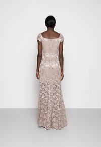 Lång, rosa spetsaftonklänning med korta ärmar och figurnära midja, som vidgar sig något vid fållen, med blommönster och en texturerad yta.