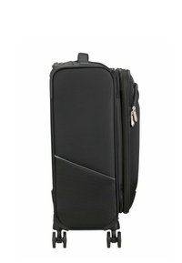 Valise souple noire à coque molle avec quatre roues doubles pivotantes, poche avant zippée et fermeture éclair d'extension du compartiment latéral.