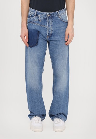 Hellblaue Jeans aus Denim mit lockerer Passform, ausgestattet mit einer aufgesetzten Tasche aus dunklerem Denim am linken Oberschenkel und leichtem Ausbleichen an den Beinen.