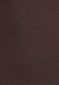 Burgundowy top z żebrowanej tkaniny z teksturowanymi pionowymi liniami, miękki materiał i taliowana forma. Brak widocznych elementów metalowych lub akcentów.