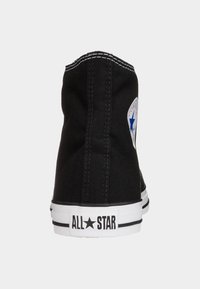 Baskets montantes en toile noire avec semelle en caoutchouc blanche et accents noirs, dotées d'un patch logo en forme d'étoile bleue sur le côté et de coutures contrastées.