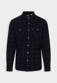 Marinblå flanellskjorta med rutig mönster i vitt, lång ärm, knäppning fram och två bröstfickor.