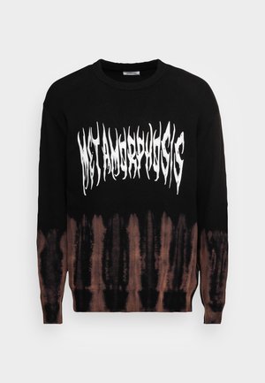 Schwarzer Pullover mit braunem Batikmuster an der Unterseite, mit fett gedrucktem weißen "METAMORPHOSIS"-Text in einer verlängerten Schriftart auf der Vorderseite.