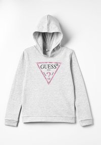 Sudadera gris claro con un bolsillo frontal, capucha con cordón y un logo triangular de "GUESS" en purpurina rosa. Fabricada en tejido de felpa suave con puños acanalados.