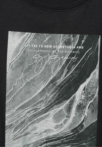 Mramorová textura s bílým textem "Řekni ano novým dobrodružstvím a sbírej vzpomínky a okamžiky" na tmavé tkanině.