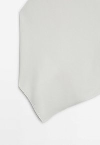Tissu gris clair avec une texture lisse, présenté plié avec un coin net visible sur un fond blanc.