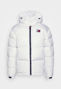 Hvid polstret jakke med høj krave, lynlås foran og marineblå detaljer. Har en logopatch og elastiske manchetter. Glat tekstur.