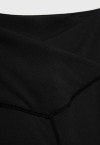 Zwarte stof met een gladde textuur. Inclusief zichtbare naden en een lichte glans. Heeft een gelaagd effect met overlappende secties.